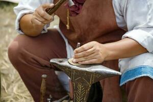 Close up image of the artist at work. He is carefully using a hammer made a decoration photo