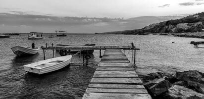 Black and white panoramic view of wooden pier and  boats photo