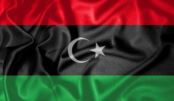 Libya flag waving fluttering in the wind with realistic texture fabric silk satin background photo