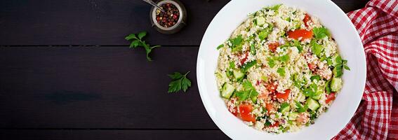 Traditional Lebanese Salad Tabbouleh. Couscous with parsley, tomato, cucumber, lemon and olive oil. Middle Eastern cuisine. Top view, banner photo