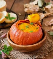 sopa de crema de calabaza con pimientos y hierbas en una calabaza foto