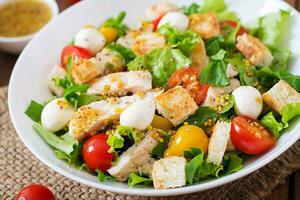 Ensalada fresca con pechuga de pollo, rúcula, lechuga y tomate. foto