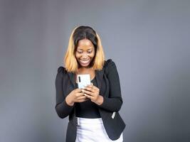 Black lady texting on her phone standing over a gray studio wall background photo