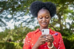 pretty black woman look very excited and rejoices while looking at her phone photo