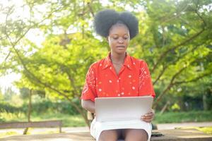 beautiful african lady outdoor using her laptop photo