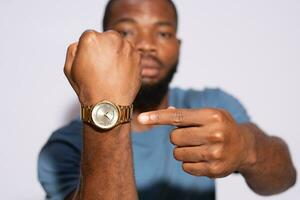 joven negro hombre demostración y señalando a su reloj de pulsera, carrera en contra hora concepto foto