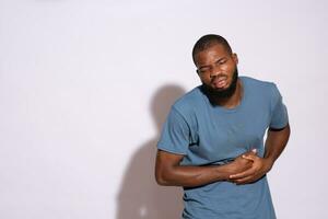 sick black man holding his stomach in discomfort photo