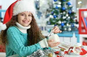 contento niña en Papa Noel sombrero sentado con Navidad presente foto