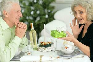 Elderly couple at the dinner table giving a New Year's gift photo