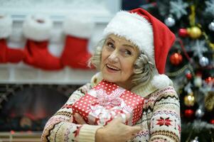 contento sonriente antiguo mujer con regalo en Navidad foto