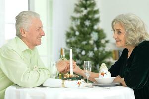 Elderly couple at the dinner table giving a New Year's gift photo