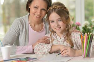 Cute mother and daughter drawing with pencils photo