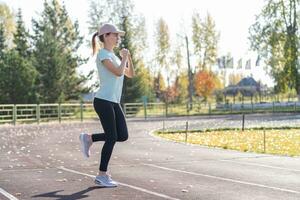 A young beautiful woman in sportswear plays sports at a local stadium photo