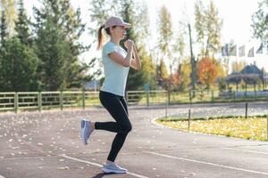 A young beautiful woman in sportswear plays sports at a local stadium photo