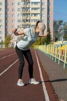 A young beautiful woman in sportswear plays sports at a local stadium photo