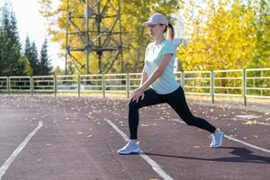 A young beautiful woman in sportswear plays sports at a local stadium photo