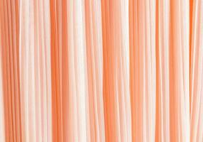 Delicate pleated pleats of silk fabric. Abstract background for design. Festive textiles. The trend of the color of the year 2024 is peach fuzz. photo