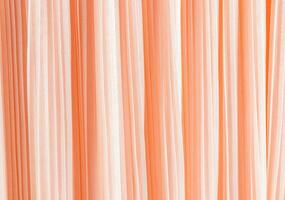 Delicate pleated pleats of silk fabric. Abstract background for design. Festive textiles. The trend of the color of the year 2024 is peach fuzz. photo