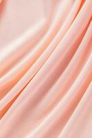 Soft pleats of peach colored satin textiles. Luxury abstract textile background design. Vertical view. Color of the Year 2024 peachy fuzz. photo