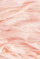 Vertical background of delicate texture of silk or chiffon fabric in peach color. Vertical view. Color of the Year 2024 Peach Fuzz. photo