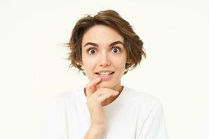 Close up portrait of woman looking with interest, listening, staring with curiosity, gasping at camera, standing over white background photo