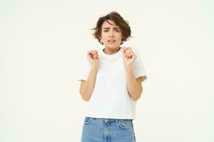 Image of woman with scared face, looks frightened, worried, trembling from fear, isolated against white background photo