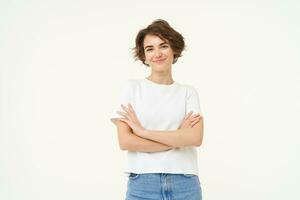 Portrait of woman standing in power pose, confident expression, cross arms on chest and smiles, stands over white background photo