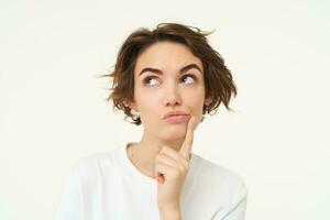 Close up portrait of woman with thoughtful face, thinking of solution, pondering, making choice, standing over white studio background photo