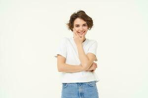 protección de la piel y mujer belleza concepto. retrato de joven sonriente mujer, toques su rostro, mirando a cámara, disfruta suave facial piel después protección de la piel rutina, blanco estudio antecedentes foto