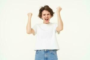Portrait of woman celebrating, winning prize, triumphing, standing over white studio background photo