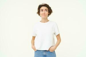 Portrait of confused brunette woman, looks up, thinking, looks unsure, standing in doubt against white background photo