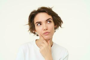 Close up portrait of woman with thoughtful face, thinking of solution, pondering, making choice, standing over white studio background photo