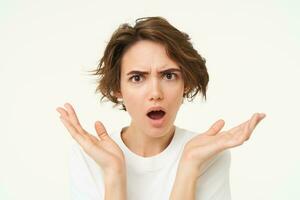 Close up of shocked brunette woman, shrugging and looking disappointed, posing over white studio background photo