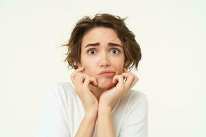 Close up of shocked, scared and worried young woman, trembling from fear, posing over white background photo