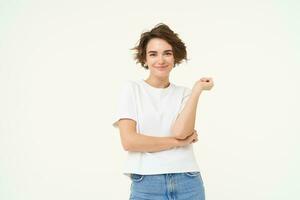 retrato de mujer en pie en poder pose, confidente expresión, cruzar brazos en cofre y sonrisas, soportes terminado blanco antecedentes foto