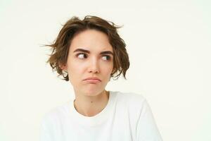 Close up portrait of shocked woman looking insulated, bothered by something, pouting and sulking, posing over white background photo