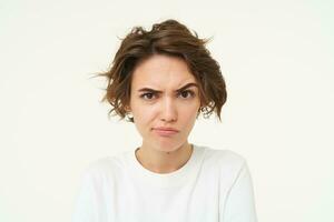 Portrait of serious, thoughtful woman with frowning face, looking suspicious, posing over white studio background photo