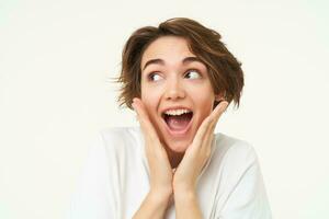 Fantastic news. Portrait of amazed young woman, looks surprised, gasps impressed, stands over white background photo