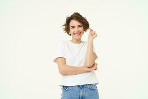 Portrait of carefree woman laughing, posing with confidence, looking self-assured and smiling, standing over white background photo