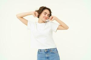 Portrait of smiling, pleased woman stretching hands, waking up after sleep, standing over white background photo