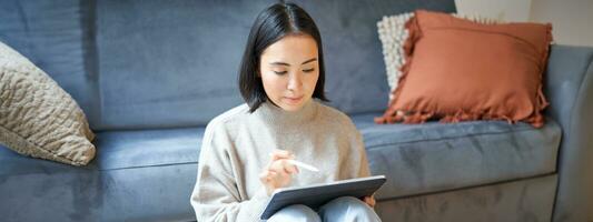 Creative young woman sitting with tablet and pen, drawing on digital application photo