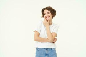 Portrait of young woman in casual clothes, laughing and smiling, touching her face without blemishes, standing over white background photo