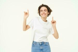 retrato de contento sonriente mujer en inalámbrico auriculares, bailando y escuchando a música, disfrutando su favorito canción, posando terminado blanco antecedentes foto