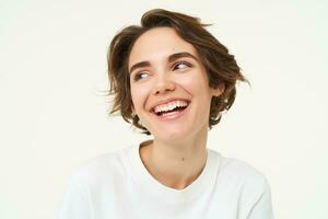 Close up portrait of brunette woman laughing and smiling, express genuine emotions, posing against white studio background photo