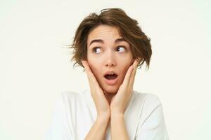 Fantastic news. Portrait of amazed young woman, looks surprised, gasps impressed, stands over white background photo