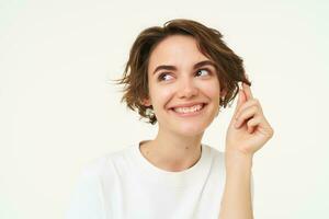 Close up of cute brunette girl playing with her hair, posing over white studio background photo