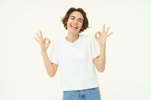 Image of smiling, happy girl shows okay, ok sign, recommending, like and approve something good, standing over white background photo