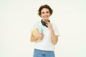 Image of stylish, modern girl student, holding workbook, documents. Woman teacher with papers standing over white background photo