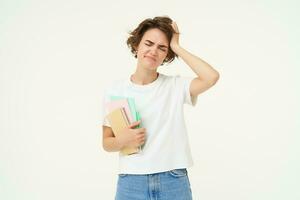 Troubled woman touches her head, looks upset, holds documents, standing frustrated against white studio background photo