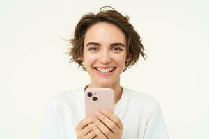 Close up of laughing smiling woman, holding smartphone, using mobile app, online shopping in application, scrolling social media, standing over white background photo